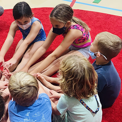 Image of boys and girls in gymnastics class touching toes.